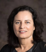 Headshot of Tamar Heller, a person with dark hair smiling and wearing black.